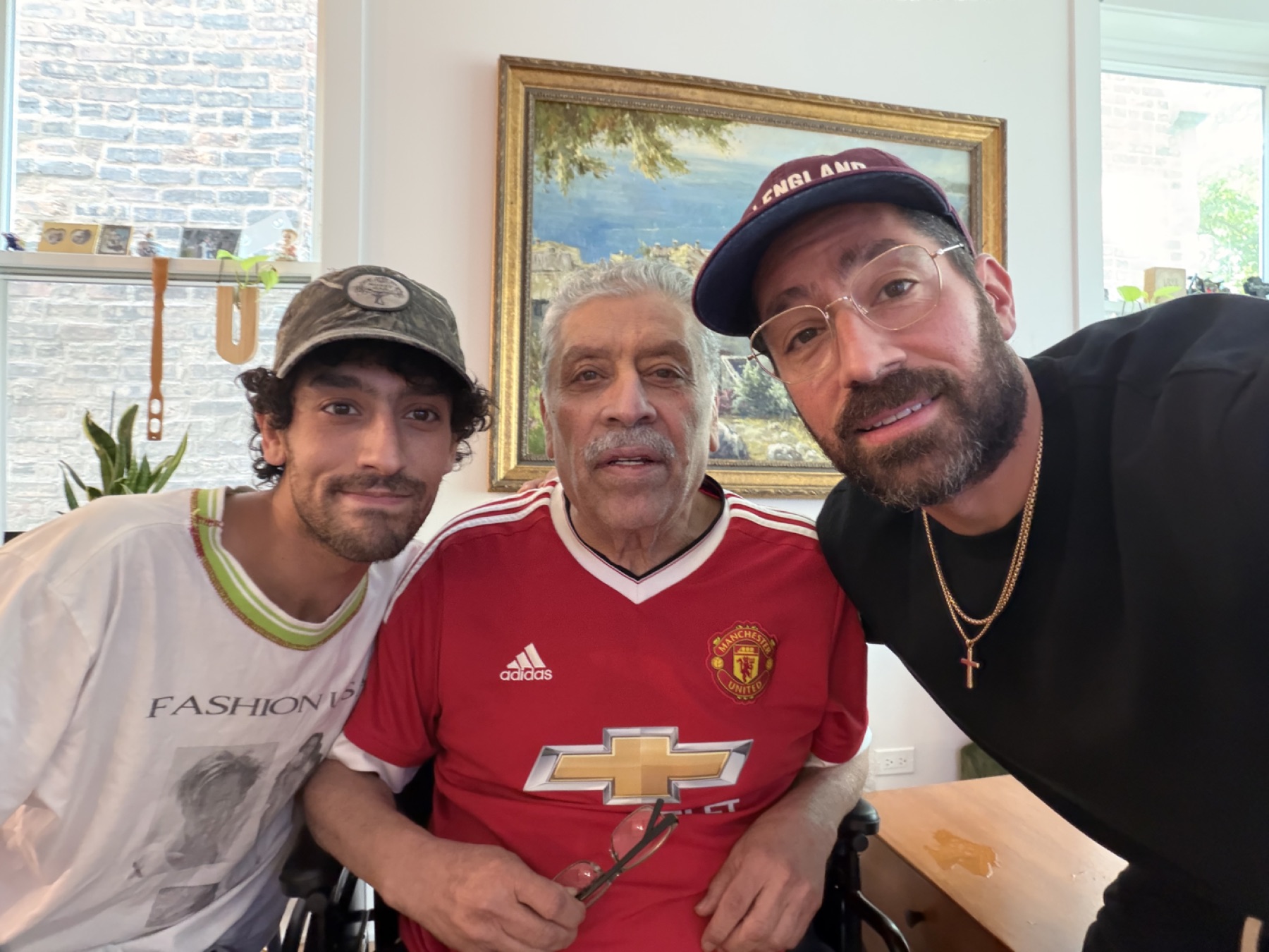 Jamal Khalilian at home in his Manchester United shirt, his sons Joshua and Johan on either side of him.